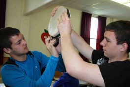 Willis Renouf and Jeremy Cormier secure a tied rawhide onto a drum frame.